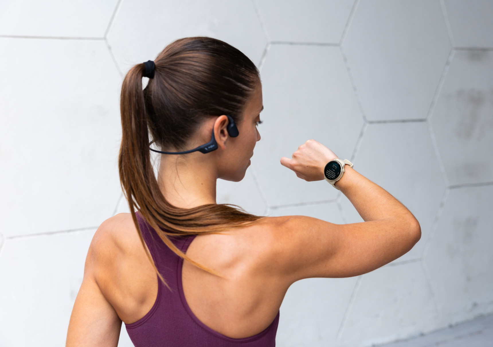 vrouw met shockz kijkt op garmin horloge