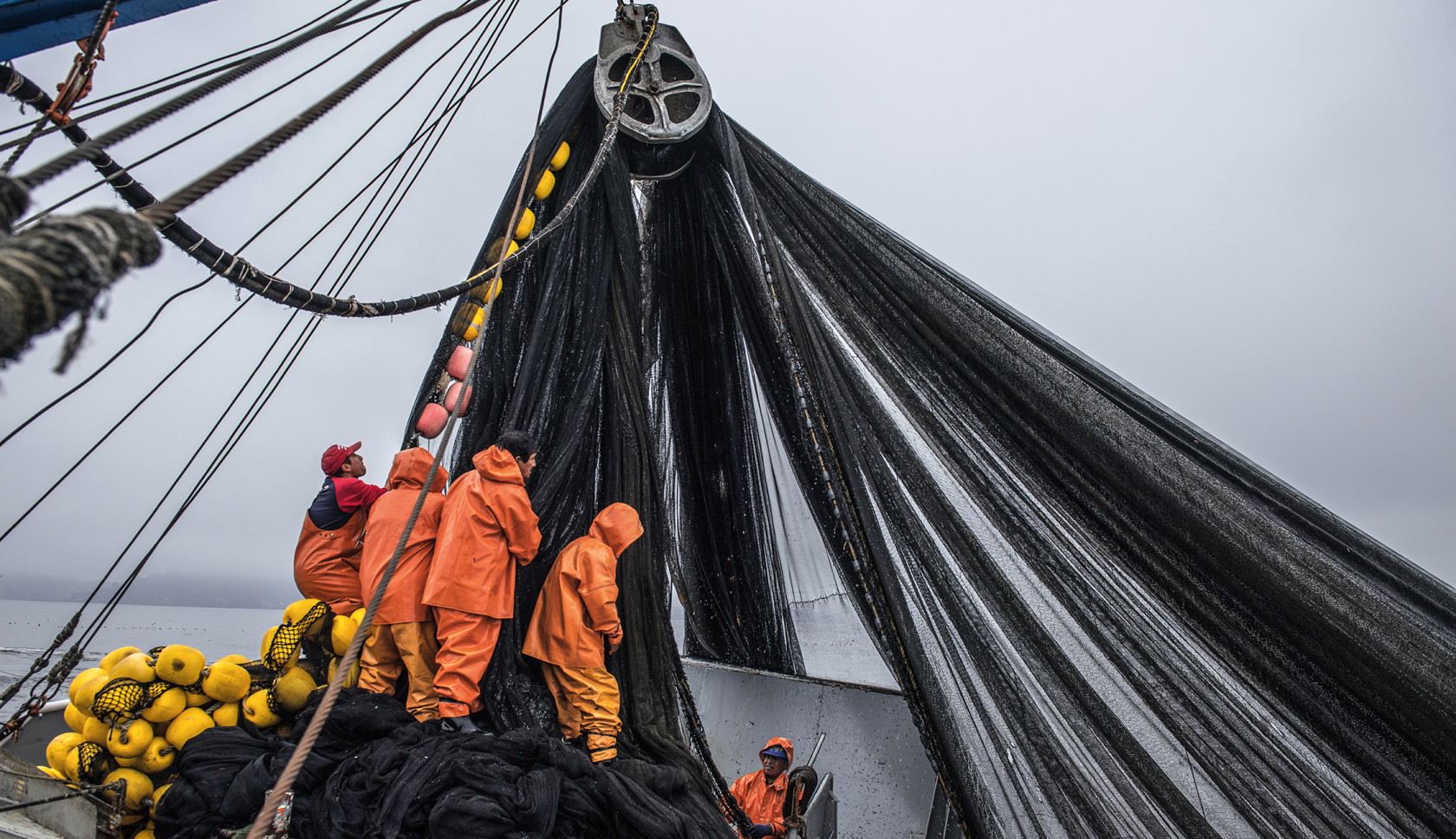 Vissers halen een groot visnet binnen op zee.
