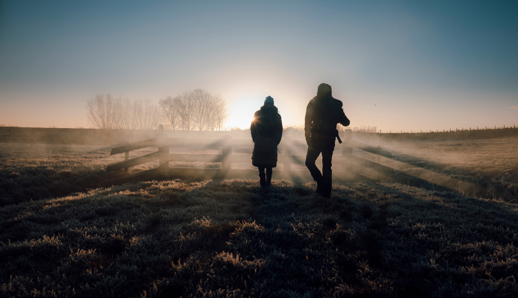 Twee mensen lopen het licht tegemoet in het winterse ochtendgloren