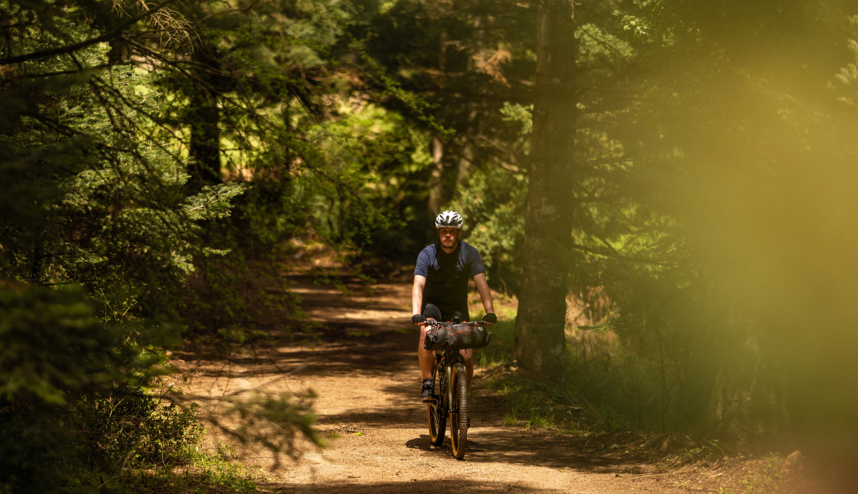 Een bikepacker fietst rustig door het bos op een gravelbike.
