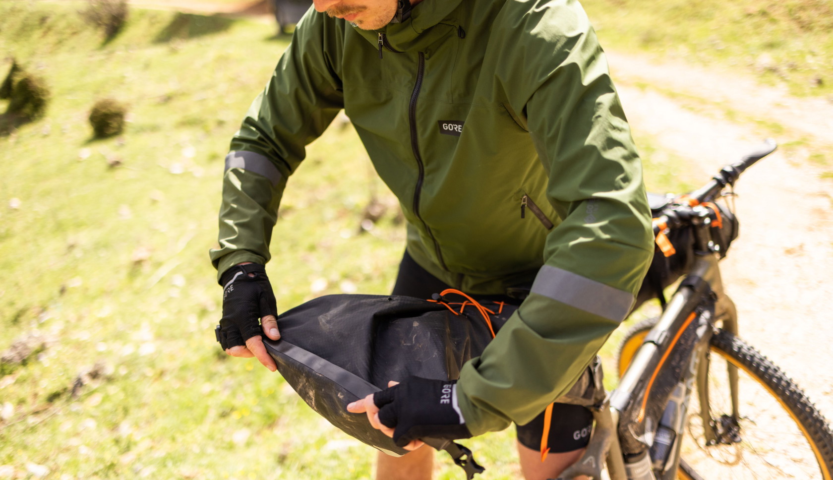 Iemand die aan het bikepacken is rolt zijn fietstas dicht.