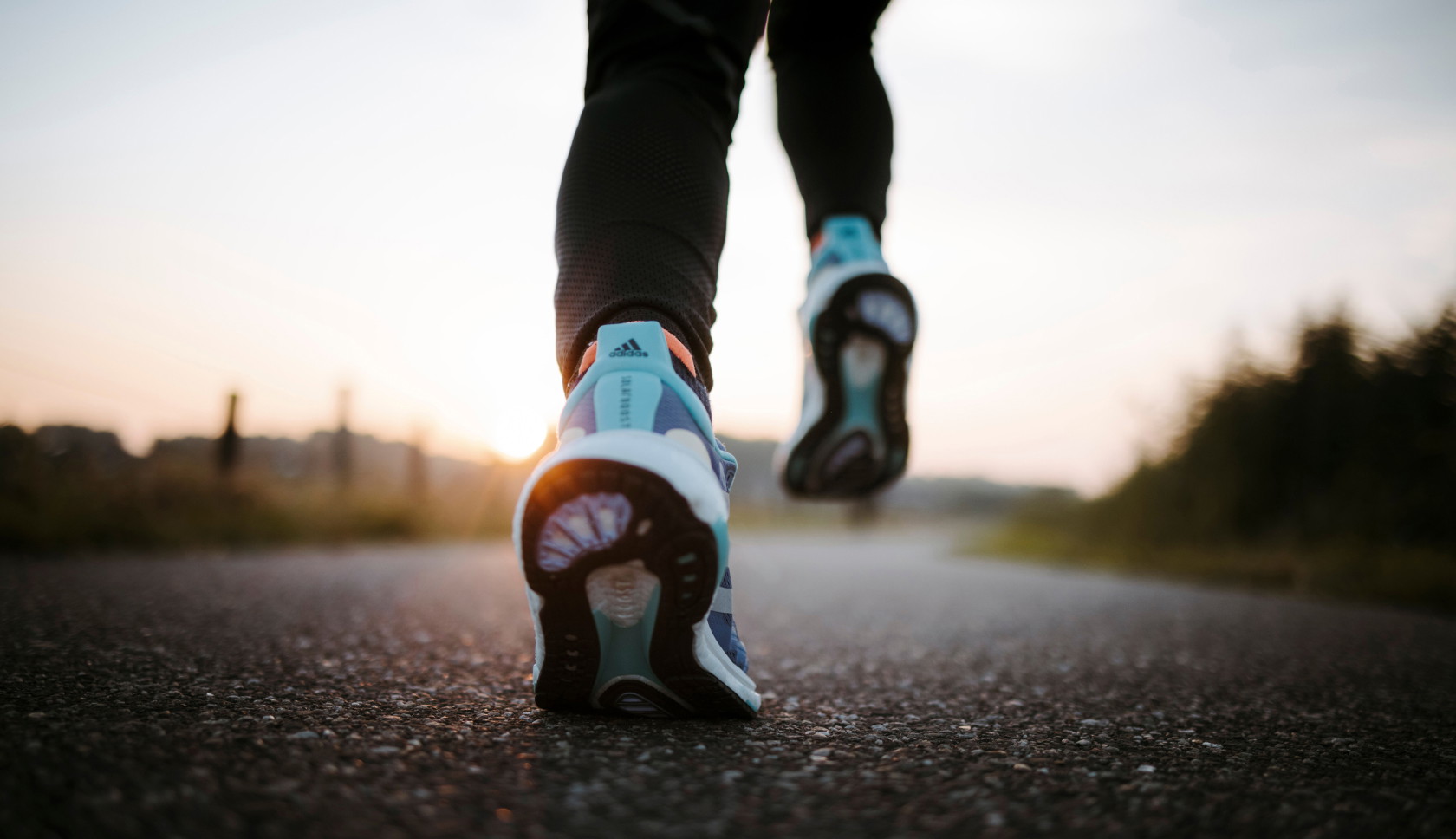 Hardloopschoenen op een weg bij vroeg ochtendlicht