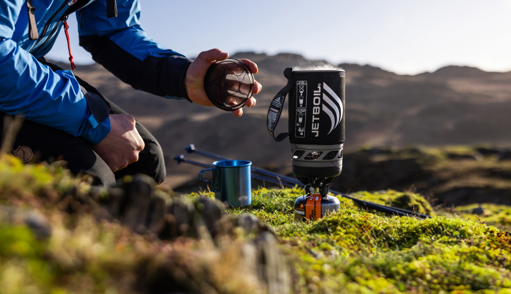 Een jetboil met kokend water staat op een ondergrond van mos