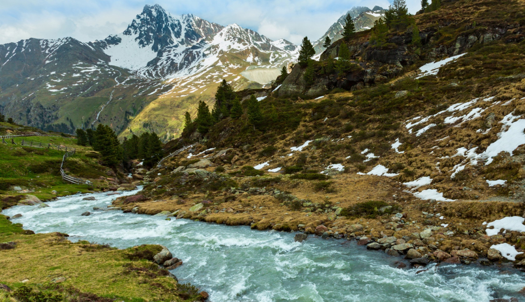 Berglandschap in het Kaunertal met rivier, naaldbomen en besneeuwde bergtoppen