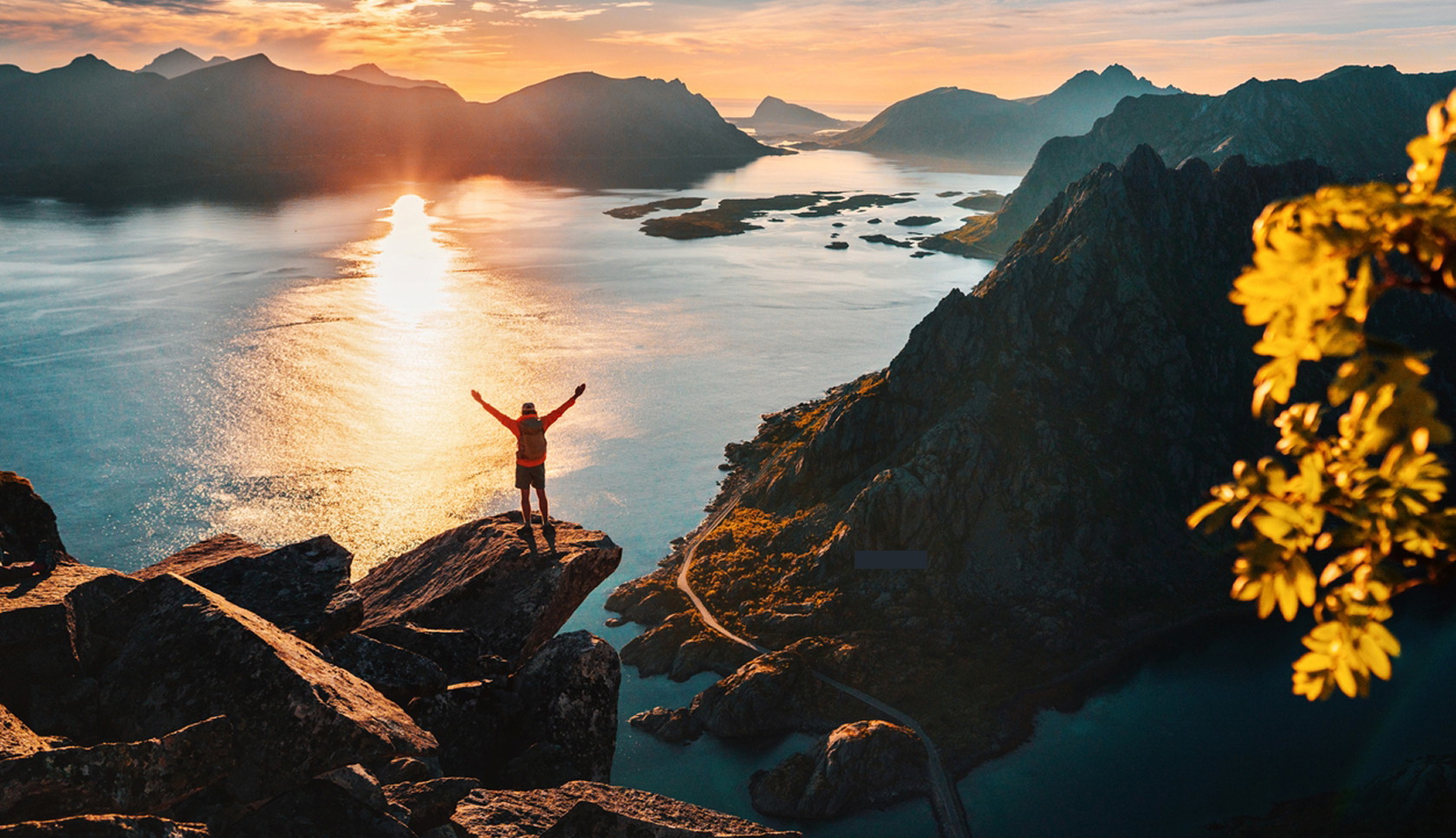 Wandelaar kijkt uit over fjorden en bergen van de Lofoten bij zonsondergang