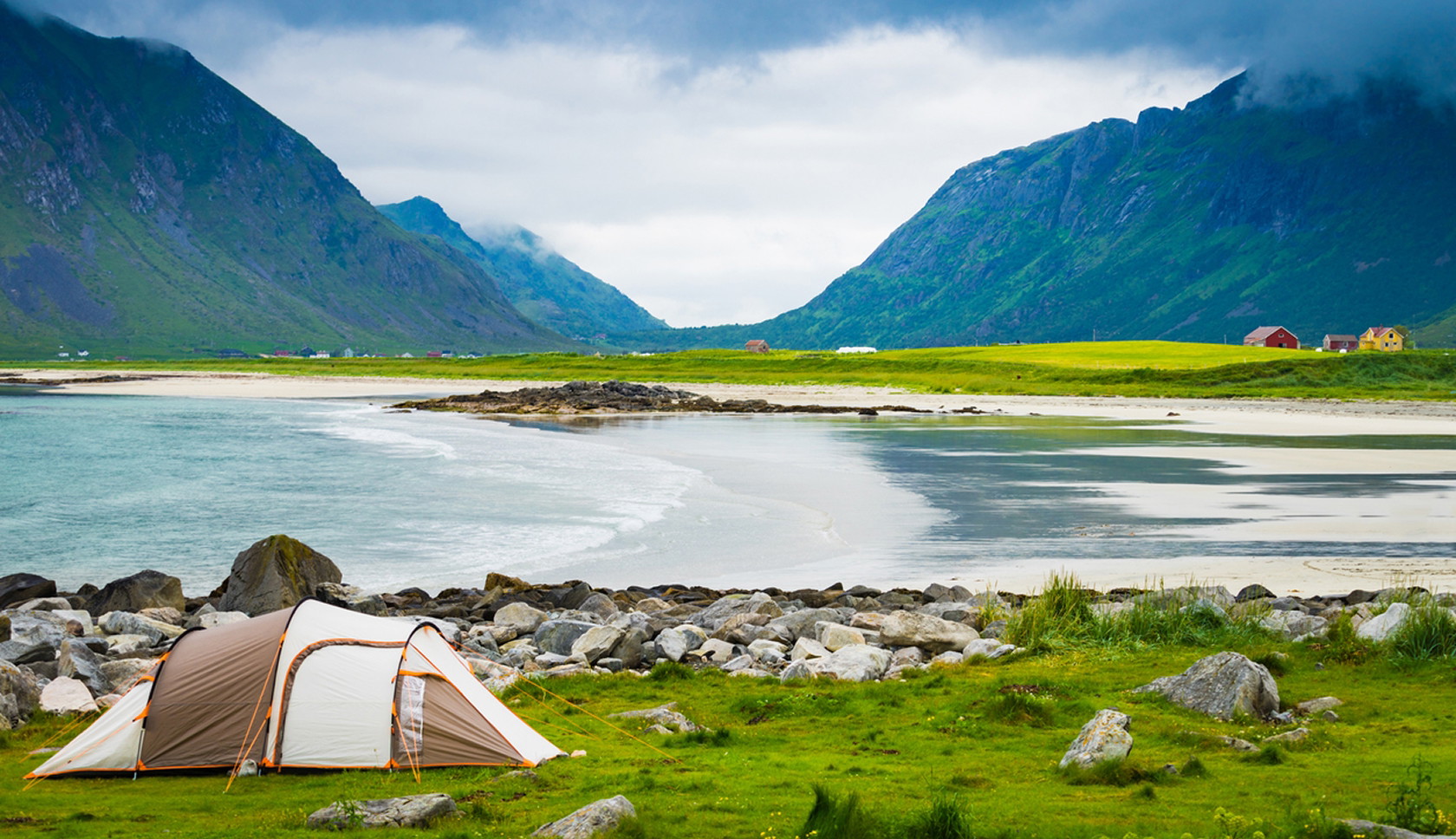 Wit zandstrand aan zee tussen groene bergen op de Lofoten in Noorwegen