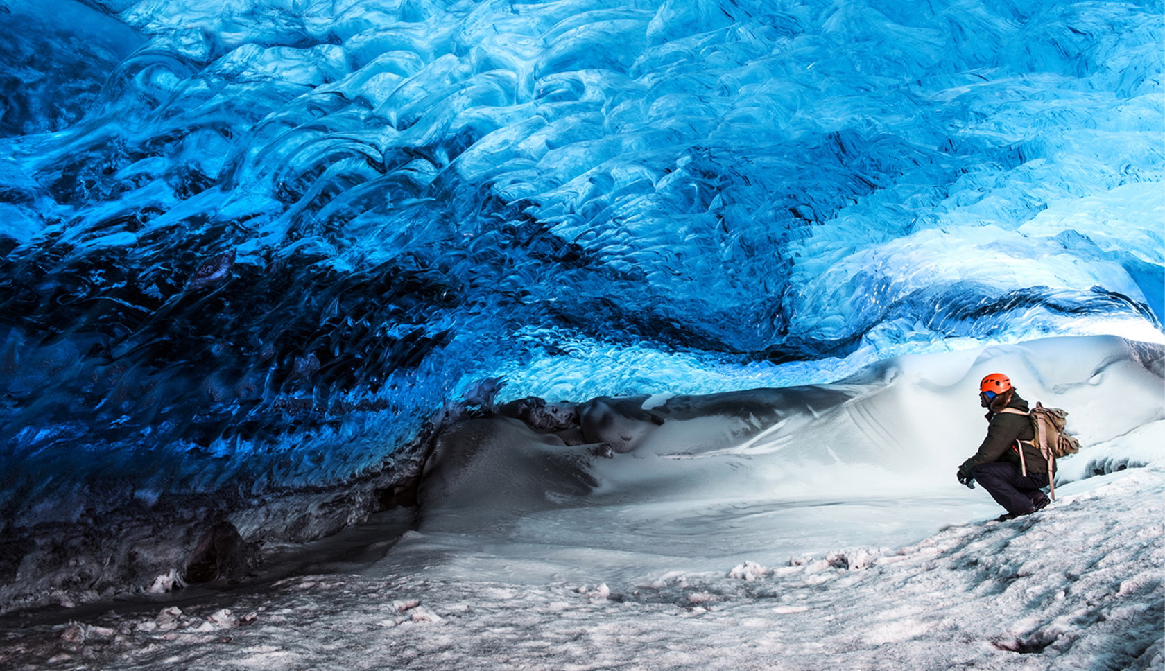 Wandelaar in een blauwe ijsgrot bij een gletsjer in Skaftafell, IJsland