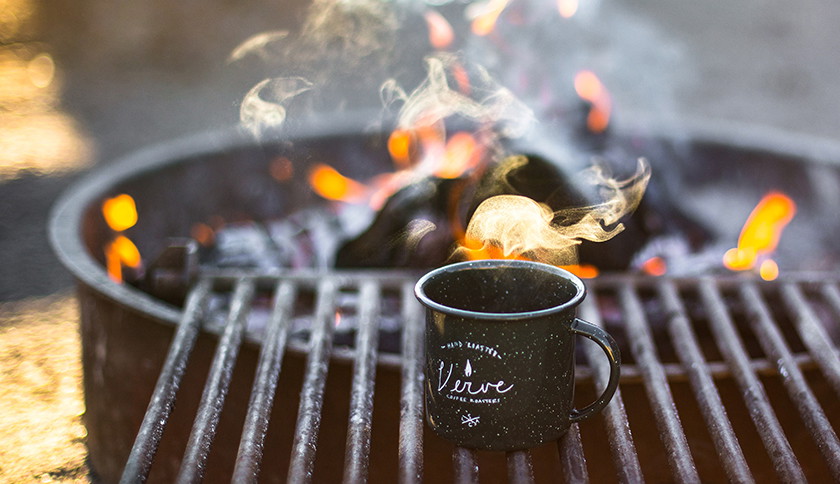kopje koffie aan opwarmen naast vuur