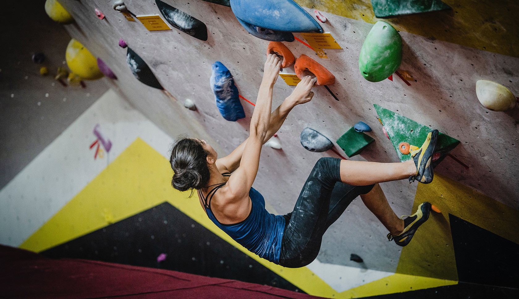 vrouw hangt aan een bouldermuur