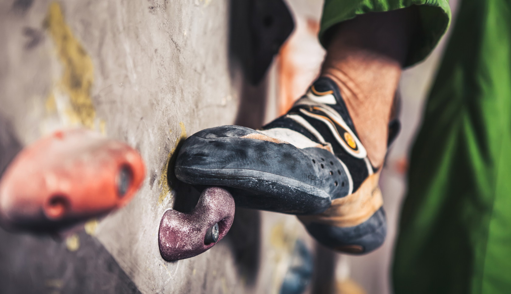boulderschoentje staat op een klimgreep tegen een bouldermuur