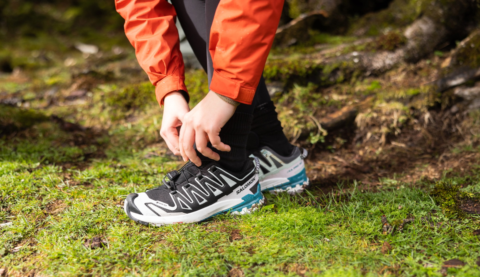 Iemand strikt de veters van lage, zwarte wandelschoenen in het bos