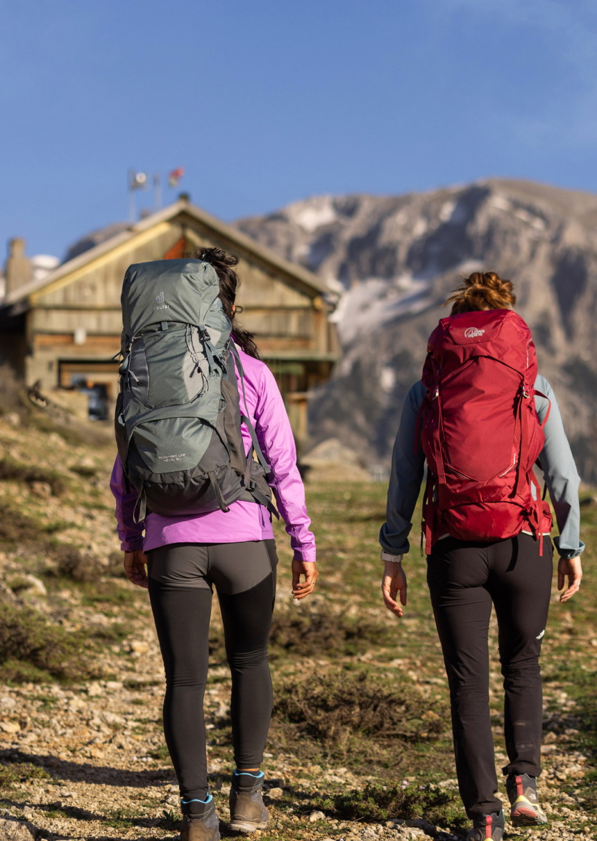 twee vrouwen met backpacks wandelen richting hut in de bergen