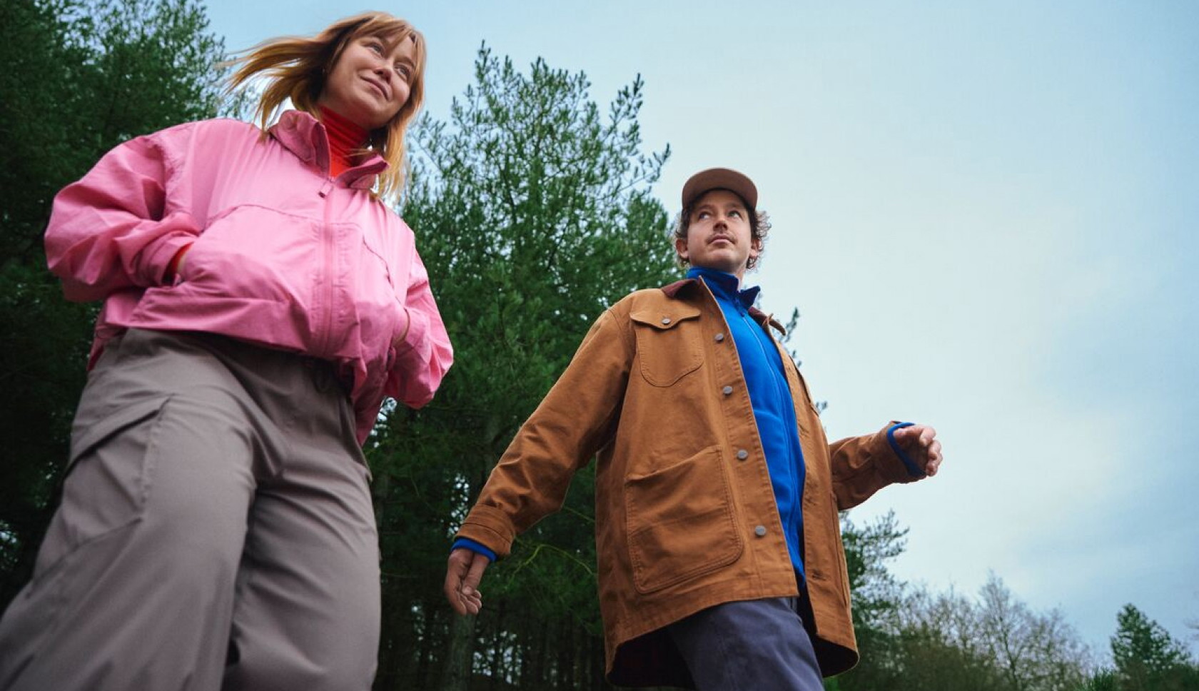 Vrouw in een kleurrijke fleecetrui geniet van de buitenlucht in een bos.