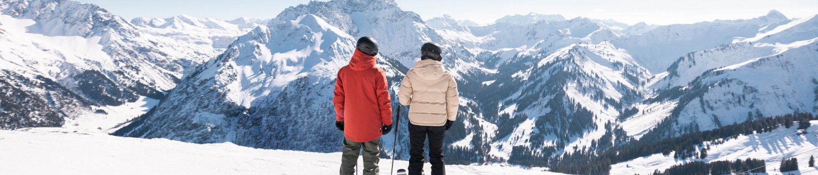 twee wintersporters kijken uit over de bergen