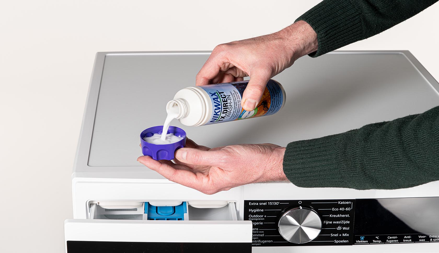 handen schenken nixwax reiniger in een cup voor de wasmachine